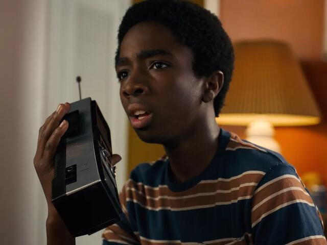Photo of black boy holding a walkie talkie listening to someone on the other end.
