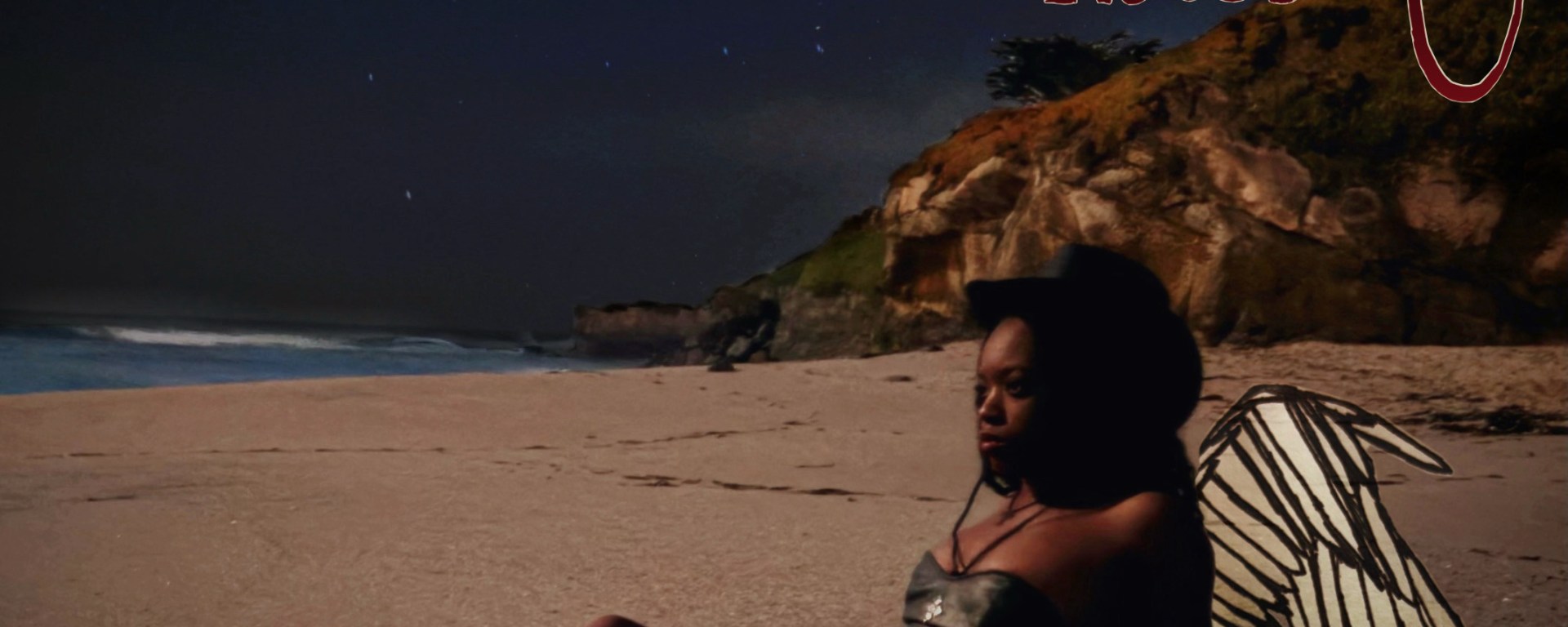 Aubrie sitting on the beach with wings